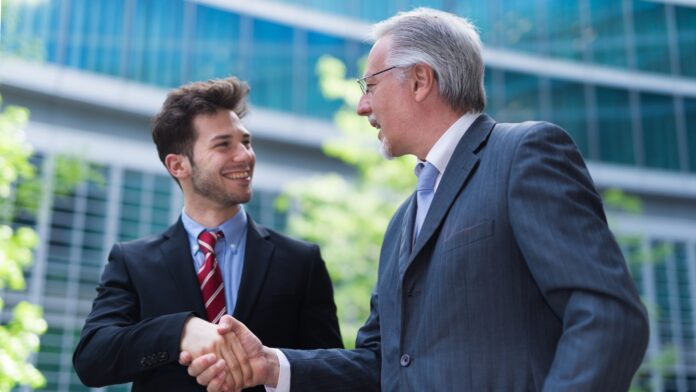 a man in suit shaking hands with another man in suit